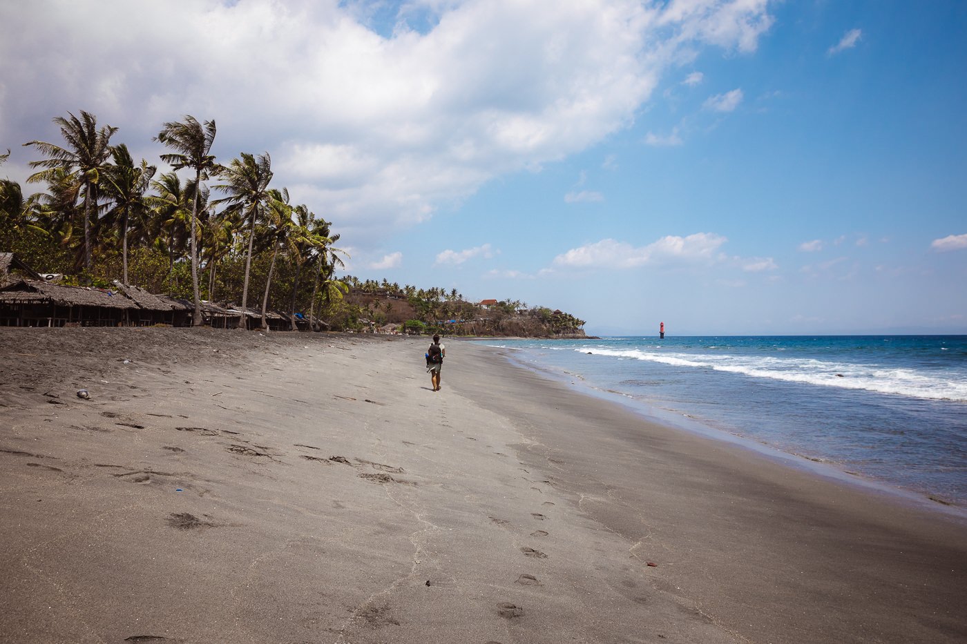 Senggigi Beach: An Honest Guide to Lombok's Old Hub 2 A single person walking the sand on the Senggigi coast with a jetty and headland behind